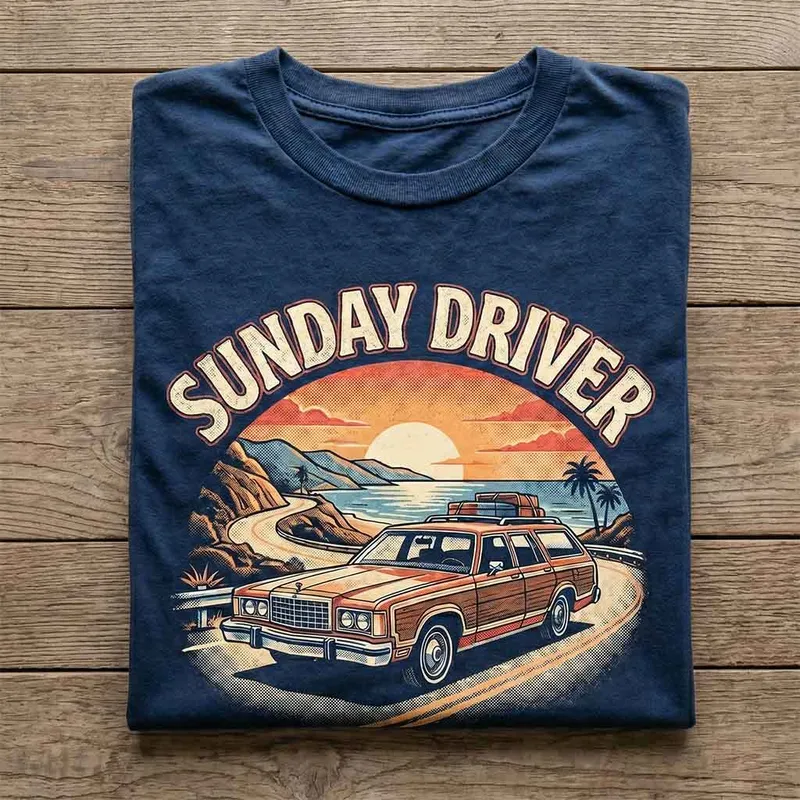 A folded navy t-shirt with a Sunday Driver print on a wooden table